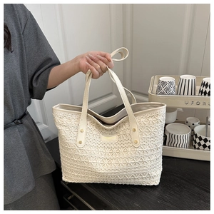 Detail of hollow woven texture and sturdy dual handles on a beige straw tote bag