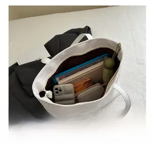 Detail view of large white woven tote bag interior showing capacity for tablet and items