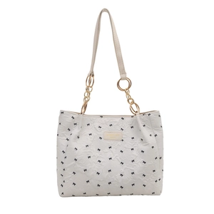 White printed tote bag with bow patterns and gold chain straps on white background