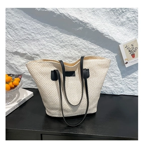 Détail du sac cabas en paille tissée avec bandoulière en cuir noir et empiècement carré