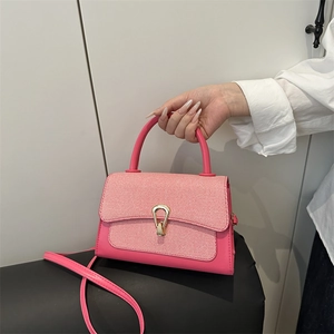 Detail of pink crossbody bag with textured flap and gold-tone horseshoe buckle