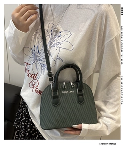 Close-up of green woven texture shell bag with silver dual zipper and top handle