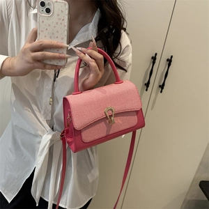 Detail of pink leather handbag featuring a red and white checkered flap and gold clasp