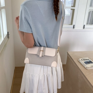 Detailed side view of grey textured crossbody bag with cream leather trim and gold buckle