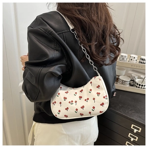 Détail du sac à bandoulière blanc avec motif de cerises rouges et bandoulière en chaîne