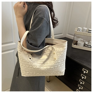 Detail of white crochet tote bag with leather handles and metallic brand logo