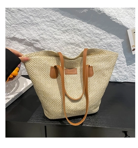 Gros plan sur la texture en paille tressée et la poignée en cuir marron du sac seau chic