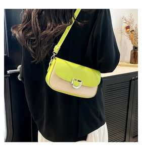 Détail du sac bandoulière vert citron et beige avec boucle argentée sur un mannequin
