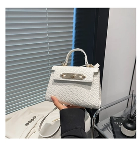 Detail of white crocodile pattern mini handbag with gold metal lock and leather strap