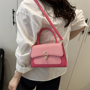 Chic pink leather and red plaid crossbody bag with a gold horseshoe lock on a model