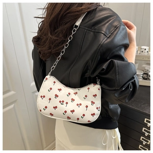 Gros plan du sac blanc avec imprimé cerise et bandoulière chaîne sur le modèle