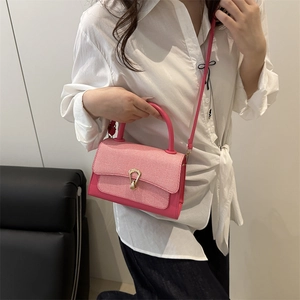 Detail view of pink leather crossbody bag with woven flap and golden horseshoe lock