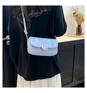 Détail d'un sac à bandoulière bleu avec texture tissée et boucle métallique argentée