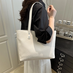 White woven leather tote bag shown on a model to demonstrate large capacity and size