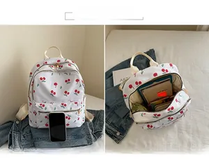 Detailed view of white canvas backpack featuring cherry prints and spacious interior main pocket
