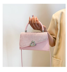 Detail of pink fashion handbag with sparkling glitter flap and heart-shaped metal lock