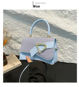 Close-up of light blue handbag with striped fabric flap and gold D-shaped buckle detail