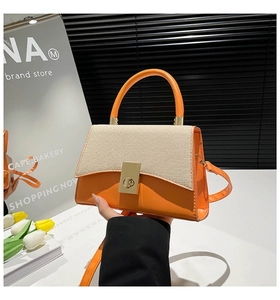 Detail of orange handbag with woven texture flap and golden clasp on modern background