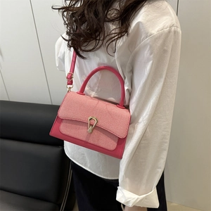 Detail of rose red crossbody bag featuring textured woven flap and gold metal buckle