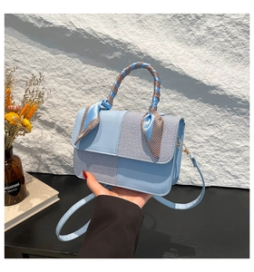 Detail of light blue crossbody bag with silk scarf handle and leather fabric patchwork