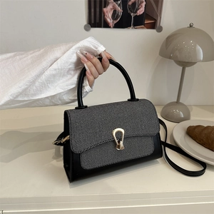 Close-up of a chic crossbody bag with grey twill flap and golden teardrop buckle detail