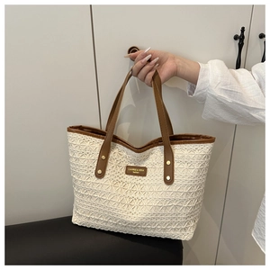 Detail of hollow-out woven tote bag with beige lace pattern and brown leather straps