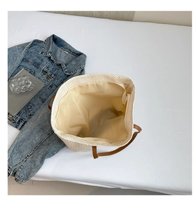 Gros plan du sac seau tissé avec poignées en cuir marron et doublure intérieure zippée
