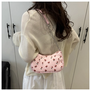Sac à épaule rose avec motif cerise et bandoulière en chaîne sur un modèle
