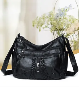 Detail of black soft leather crossbody bag with multiple zipper pockets and woven trim