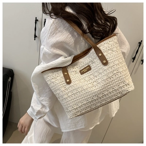 Close-up of beige lace woven tote bag featuring brown leather straps and rivet details