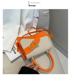 Detail of orange and beige leather handbag with large gold D-shaped buckle and crossbody strap