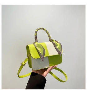 Detail of two-tone green and beige handbag with decorative scarf and adjustable strap