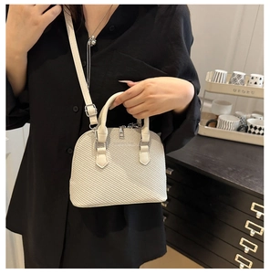 Close-up of white woven shell bag texture with silver adjustable buckle strap