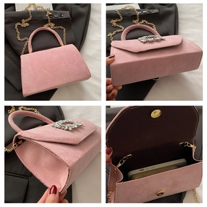 Detail view of pink suede handbag with square rhinestone buckle and golden chain strap