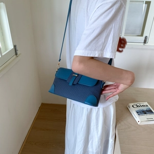 Blue fabric and leather patchwork crossbody bag shown on a model in a bright interior