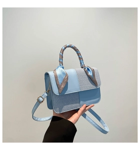 Detail view of light blue textured handbag with decorative check pattern scarf on handle