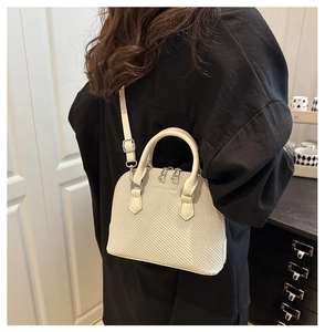 Detail showing cream shell bag texture with silver hardware and adjustable strap
