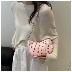 Sac hobo rose imprimé cerise avec chaîne argentée porté sur un pull blanc texturé