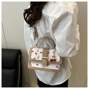 Dettaglio borsa in pelle bianca con stampa ciliegie e accessorio decorativo ciliegia