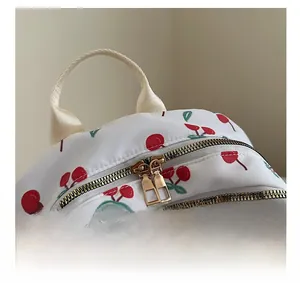 Detail view of smooth metal double zippers and cherry print on white nylon backpack