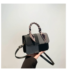 Detail of contrast stitch handbag with silk-wrapped handle and golden hardware finish