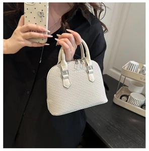 Detailed view of white shell bag with knit texture and silver hardware held by a model