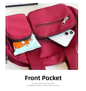 Detailed view of dual front zipper pockets on a burgundy nylon travel shoulder bag