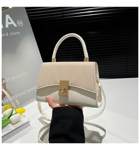 Detail of contrasting woven texture and golden rectangular twist lock on the white bag