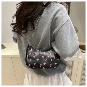 Détail d'un sac demi-lune noir avec imprimé cerises et fine bandoulière chaîne