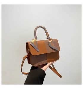 Detail of a brown patchwork handbag with woven texture and silk scarf wrapped handle