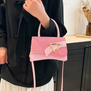 Detail of pink patchwork crossbody bag featuring a golden D-ring buckle and leather strap