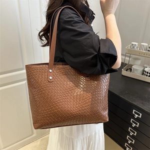 Detail of a brown woven leather tote bag showing spacious capacity and shoulder strap