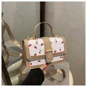 Dettaglio della mini borsa bianca con stampa a ciliegie e rifiniture color kaki