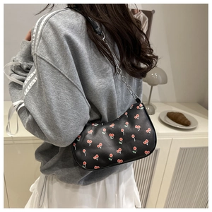 Détail du sac bandoulière noir imprimé cerises avec chaîne argentée sur modèle